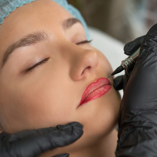woman receiving micro pigmentation treatment on lips from therapist with black gloves